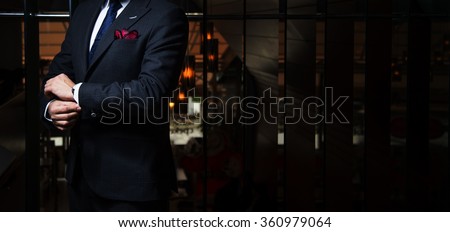 Man in suit fixing his cufflinks