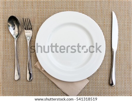 top view empty White dish with fork and spoon set on brown weave  background
