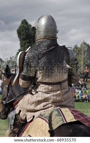 Medieval knight sitting on his horse. From behind.