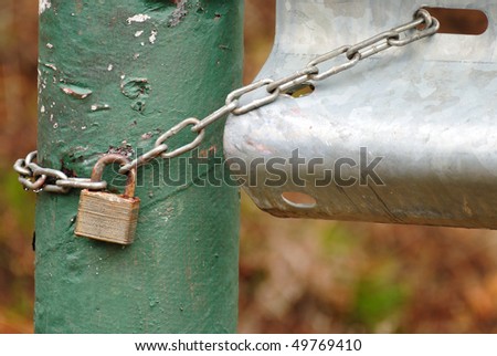 Padlock and chain securing a locked metal gate