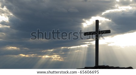Cross silhouetted against clouds and rays of the sun