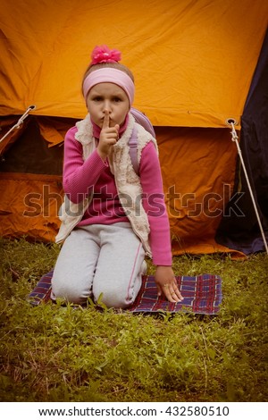 Happy child . Travel with tent . Girl young tourist . Backpacking . Tent shelter from a rain and wind . To sit on a grass . The child looks for parents