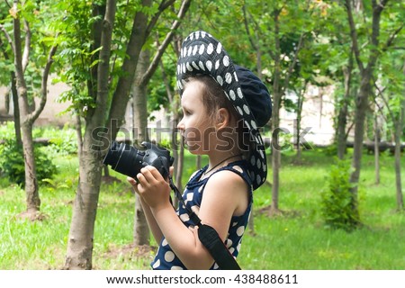 Girl photographer . To look in a lens . Happy childhood . beautiful childhood .  the advanced child . The girl in a hat from the sun. A hat in peas. Settings of a camera