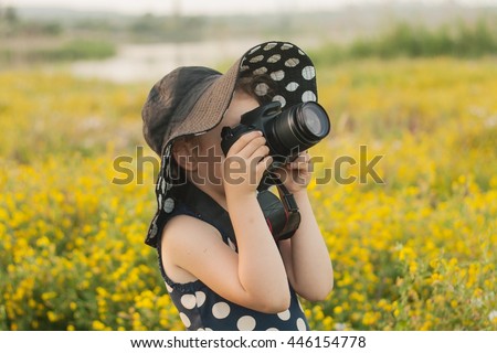 Happy childhood . beautiful childhood .  the advanced child . The girl in a hat from the sun. A hat in peas. Settings of a camera . Young girl, reflex camera and field. A summer background