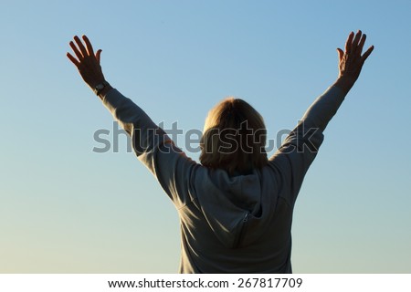 Mature woman with her hands to the sky in worship and praise and/or feeling successful.