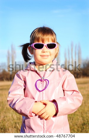 Little girl in pink coat and pink sunglasses smiling