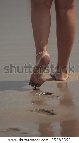 Beautiful female feet going on an ocean beach