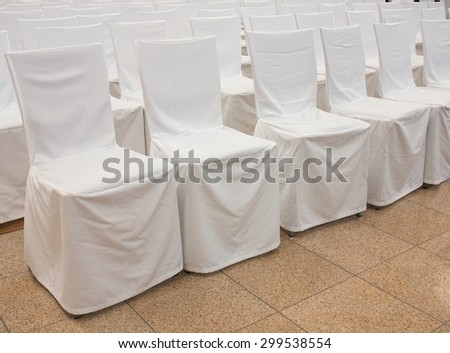 Chairs covered with a white fabric. Wedding reception.
