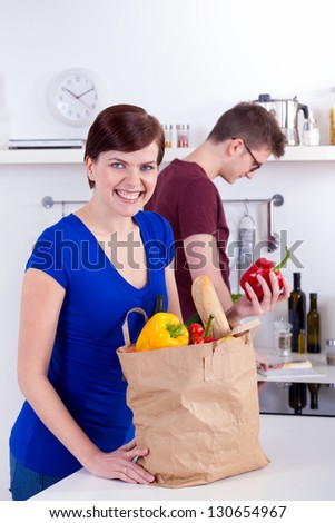 Happy woman and young man unpacking groceries in the kitchen