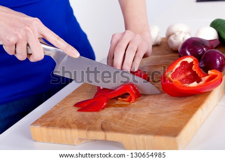 female hands chopping vegetables on a wooden board in the kitchen