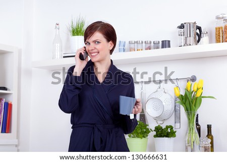 young woman having a cup of tea and talking on the phone in the morning