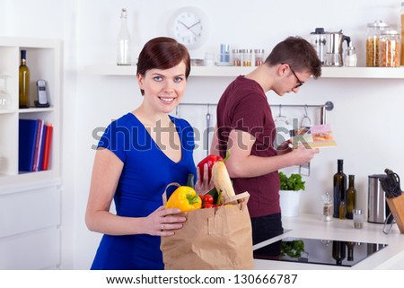 Happy woman and young man unpacking groceries in the kitchen