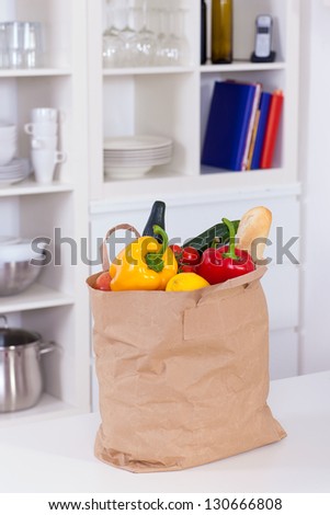 Paper shopping bag full of food on a kitchen counter