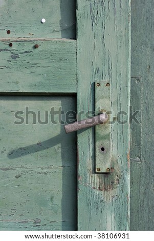 closeup shot of an old green painted wooden door and a rusty doorknob