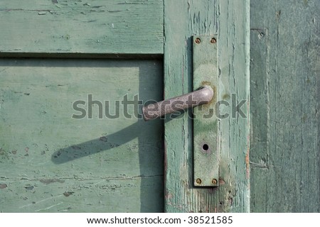closeup shot of an old green painted wooden door and a rusty doorknob