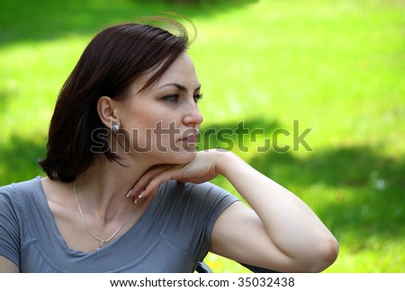 Profile of a girl sitting in the city park on the bench