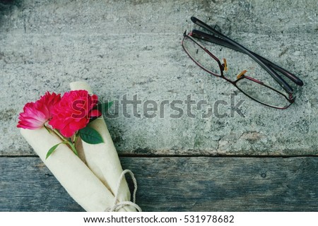 Rose and glass / spectacle on wooden background. Vintage.