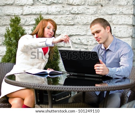 Business partners meeting: Male and female with laptop sitting outdoors
