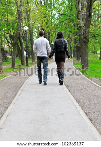Couple walking down the road in the park. From the back
