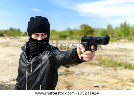 Masked gunman taking aim with a gun