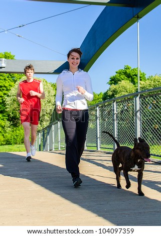 Couple running with dog across the bridge