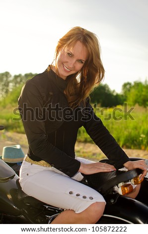 Smiling redhead girl on a motorbike on a road