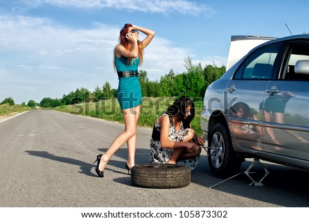 Two girls are fixing a changing a tire.