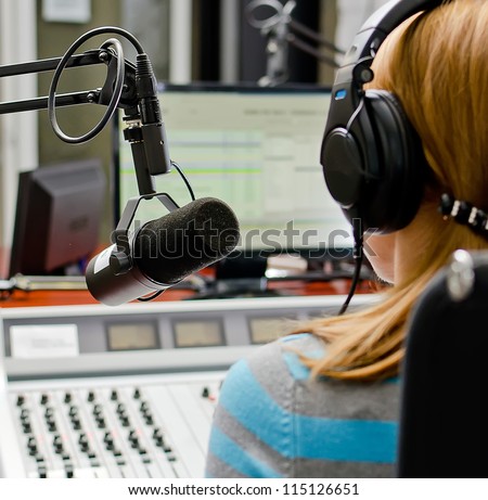 Rear view of female dj working in front of a microphone on the radio