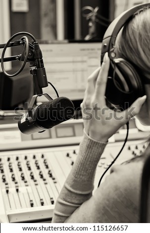 Rear view of female dj working in front of a microphone on the radio. Black and white