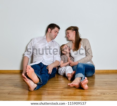 Happy family sitting on the floor against the wall