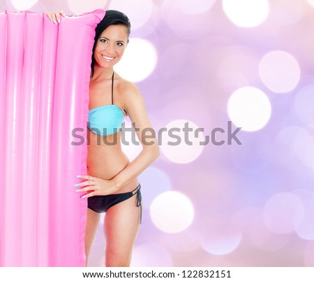Young woman holding pink inflatable mattress on purple bokeh background
