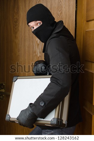 Male burglar stealing case with money