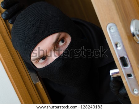 Male burglar in mask breaking into the house
