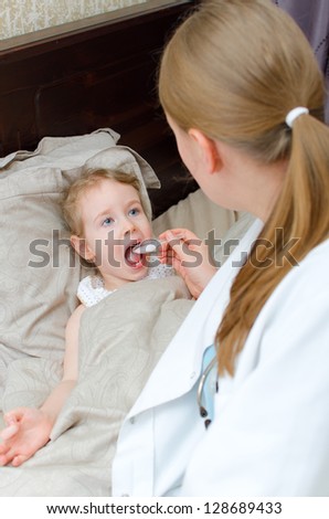 Pediatrician visiting sick child at home and giving medicine