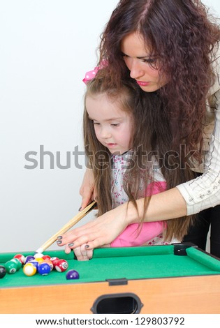 Mother teaching daughter play billiard