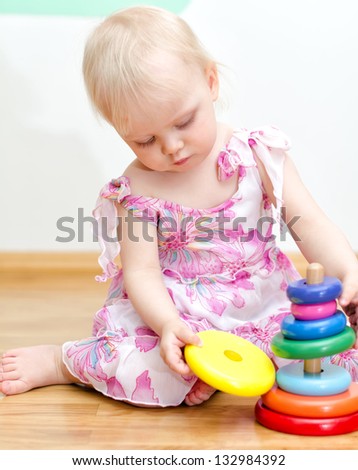 Little baby girl playing with colorful child pyramid