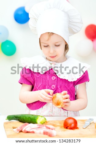 Little girl in chief hat cooking dinner
