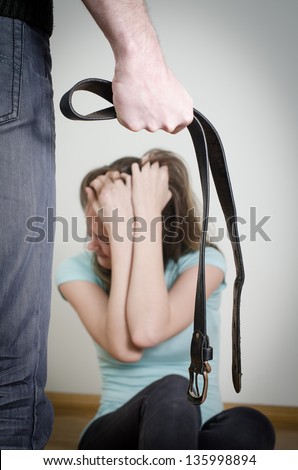 Man with belt coming to his wife. Home violence concept