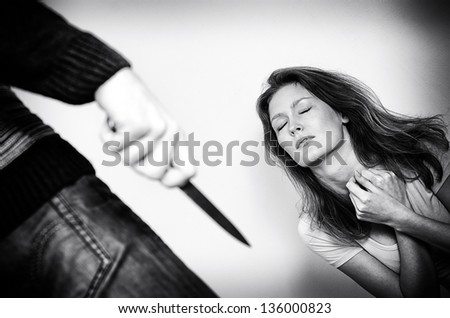 Man with knife coming to his wife. Home violence concept. Black and white
