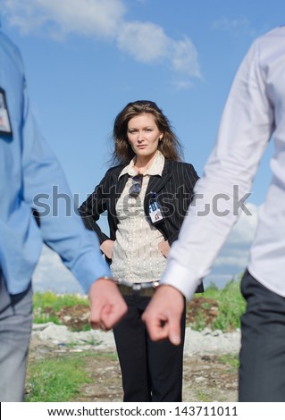 Close up view of hands in handcuffs and female FBI agent on background