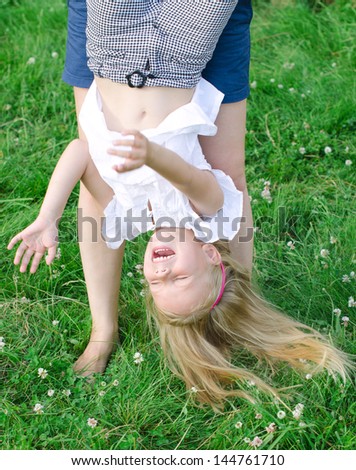 Little funny girl playing upside down outdoors