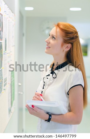 Young female student looking through job offers on board
