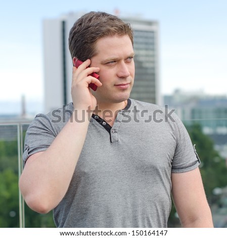 Handsome man speaking on the phone on city background