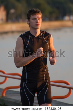 Young handsome sportsman running near the sea