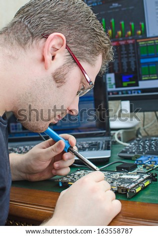 Worker repairing computer equipment with soldering iron