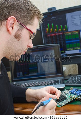 Worker repairing computer equipment with soldering iron