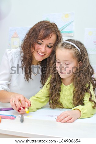 Teacher helps little girl to draw
