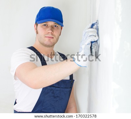 Male plasterer in baseball cap polishing the wall.