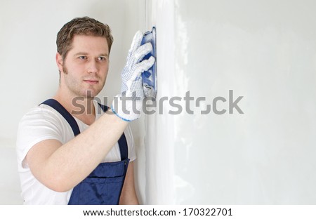 Male plasterer polishing the wall. Space for text.