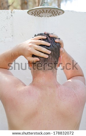 Man having shower outdoors. View from the back.